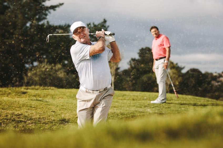 an older golfer playing a shot