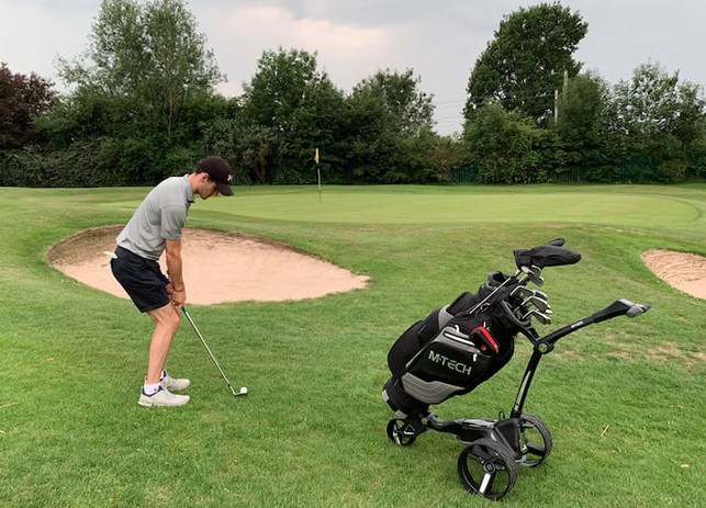 an electric golf trolley on a hilly part of the course